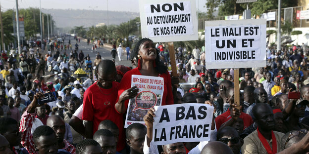 Demonstranten halten französischsrachige Schilder hoch.