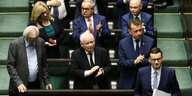Polens Premier wartet im Parlament kurz vor seiner Regierungserklärung, seine Parteifreunde klatschen