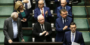 Polens Premier wartet im Parlament kurz vor seiner Regierungserklärung, seine Parteifreunde klatschen