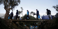 Fünf Menschen auf einer Holzbrücke über einem mit Müll gefülltem Graben