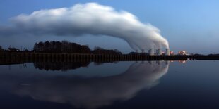 Kraftwerk mit rauchenden Schloten, der Wind biegt die Fahne