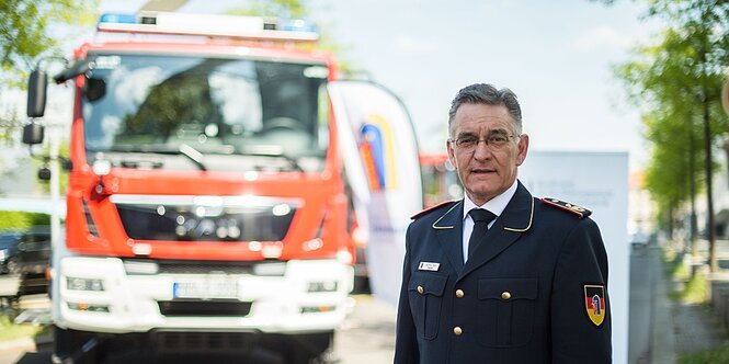 Ein Mann in Uniform steht vor einem feuerwehrauto