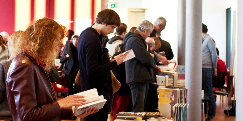 Zu sehen sind Leute vor ausgebreiteten Büchertischen beim Schmökern