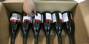Eine Hand klebt etiketten auf Weinflaschen