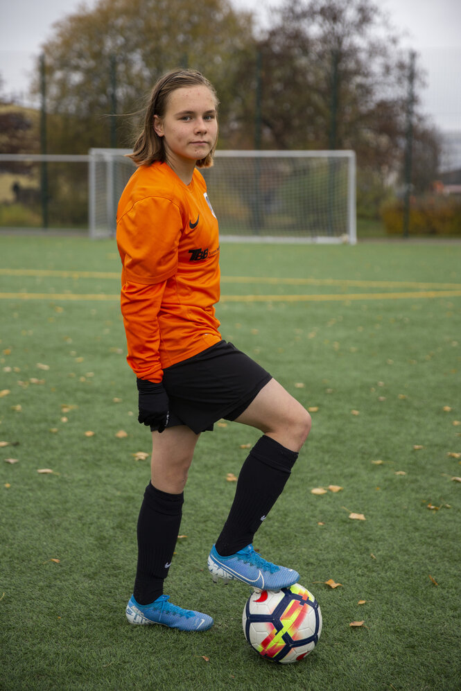 Mädchen mit Fußball auf grünem Rasen