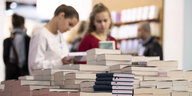 Besucherinnen blättern auf der Frankfurter Buchmesse in einem Stapel Bücher