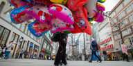 Ein Mensch läuft durch die Innenstadt von Hannover. Er trägt viele Ballone und ist offensichtlich ein Ballonverkäufer.