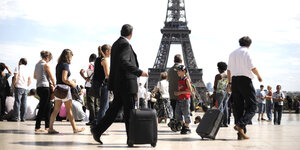 Touristen mit Rollkoffern vor dem Eiffelturm