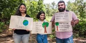 Drei AktivistInnen haben Protestplakate in der Hand und stehen nebeneinander