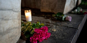 Rote Rosen und eine Kerze vor einer Gedenkstätte