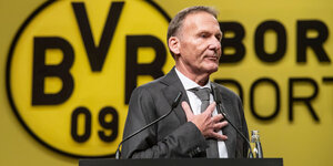 ein Mann am Rednerpult, im Hintergrund das BVB-Logo