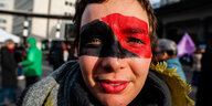 Eine Frau demonstriert mit geschminktem Gesicht