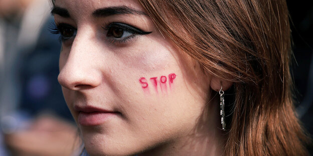 Eine Frau hat sich das Wort "Stop" auf dei Wange geschrieben