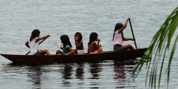 Fünf junge indigene Brasilianerinnen fahren in einem Boot
