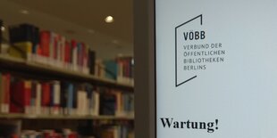 Der Bildschirm eines Computers einer öffentlichen Bibliohtek zeigt die Meldung "Wartung!". Im Hintergrund Bücherregale.