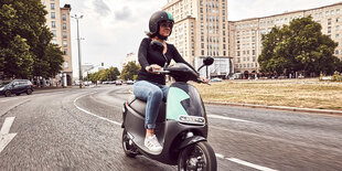 Eine Frau fährt auf einem Elektroroller durch Berlin