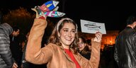 Eine junge Frau schwenkt bunte Fische aus Papier, um gegen rechtspopulistische Hetze zu demonstrieren