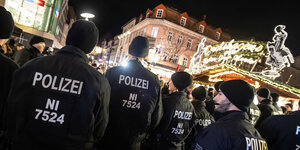 Göttingen: Polizisten stehen während einer Lesung von Thomas de Maizière (CDU) im Rahmen des ·Göttinger Literaturherbstes· vor Demonstranten auf dem Weihnachtsmarkt am Alten Rathaus