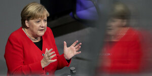 Merkel steht mit rotem Jacket am Rednerpult