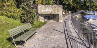 Eine Seepromenade mit einem Betonbunker am Wegrand.