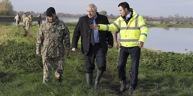 Boris Johnson in Gummistiefeln mit weiteren Männern auf einem Deich
