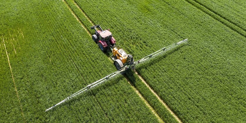 Ein Traktor fährt über ein grünes Feld