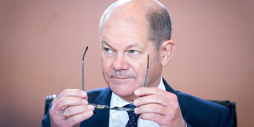 Olaf Scholz hält seine Brille in der Hand