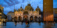 Touristen gehen über den Markusplatz in Venedig während der blauen Stunde