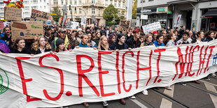 Menschen laufen hinter einem transparent auf einer Demop