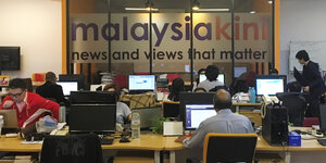 Redaktionsbüro, im Hintergrund der Schriftzug "Malaysiakini" an einer Glaswand