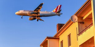 ein Flugzeug fliegt über ein Haus