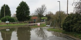 Eine riesige Wasserlache versperrt den Weg zu einem kleinen Hof