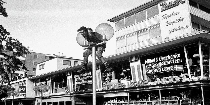 Ein junger Mann klettert auf eine Straßenlaterne in der Wolfsburger Fußgängerzone.