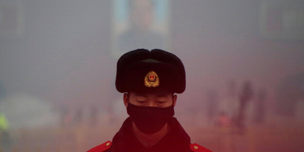Ein Polizist steht auf dem Tainanmen-Platz und träft eine Atemschutzmaske