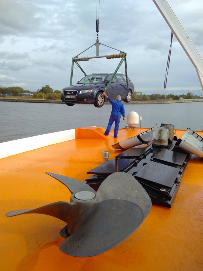 Ein Auto wird auf ein Schiff geladen