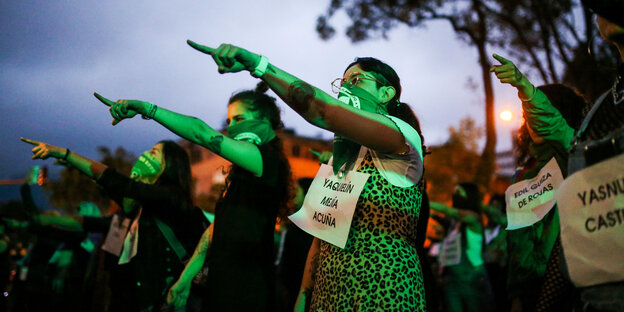 Grün angeleuchtete Frauen zeigen mit dem Finger in die Ferne