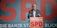 Ein Mann steht hinter einem Pult vor einer Wand, auf der "SPD" steht