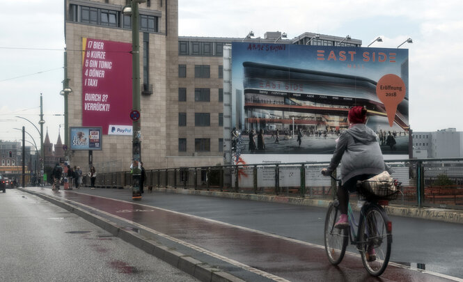 Eine Radlerin fährt vor einer Mall vorbei