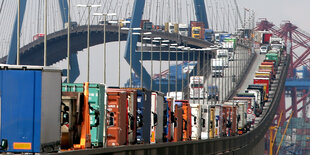 Eine doppelte LKW-Schlange bewegt sich auf eine Hängebrücke zu