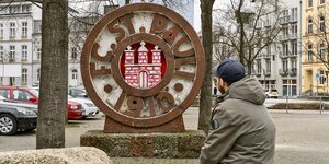 Sebastian Block blickt auf eine Skulptur, die das Wappen des FC St. Pauli zeigt.