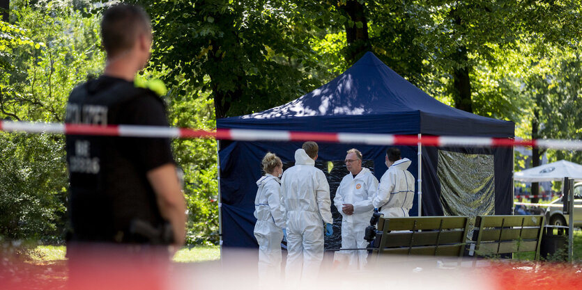 Menschen in weißen Overalls vor einem blauen Zelt