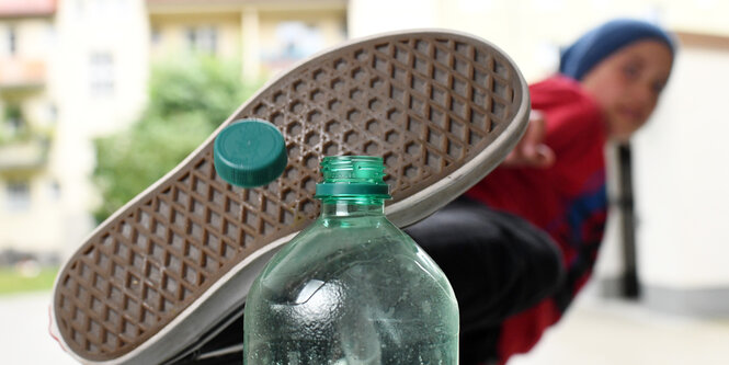 Junge tritt einen grünen Deckel von einer Plastikflasche