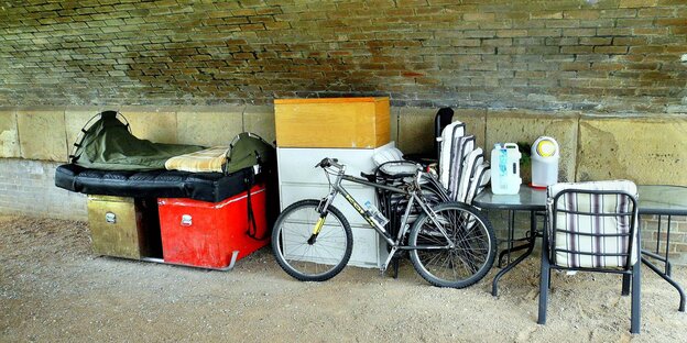 Möbelstücke, Kisten, Fahrrad unter einer Brücke