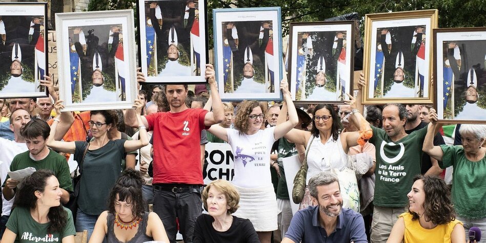 Menschen protestieren mit Fotos von Macron , die auf dem Kopf stehen