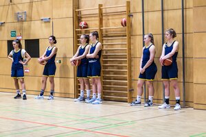Junge Basketballspielerin stehen an einer Hallenwand Junge Basketballspielerin stehen an einer Hallenwand