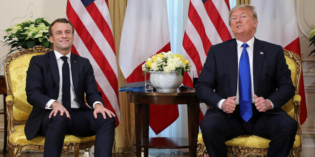 Emmanuel Macron sitzt neben Donald Trump, Macron grinst, Trump spricht.