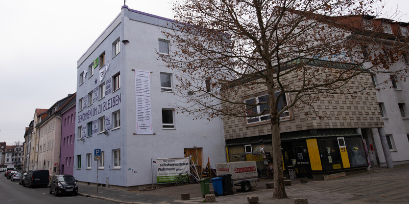 Auf einer weißen Hausfassade steht "Gekommen um zu bleiben"