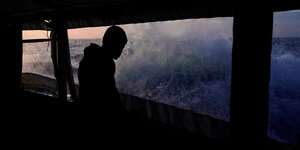 Ein Mann schaut auf hohe Wellen , die gegen eine Bootsscheibe schlagen
