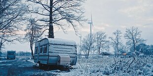 Ein Wohnwagen steht in einer trostlosen Winterlandschaft.