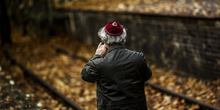 Ein Mann mit Kippa auf von Laub bedeckten Bahngleisen